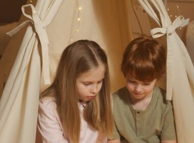 Dziecko czytające kolorową książkę edukacyjną siedzi na podłodze.