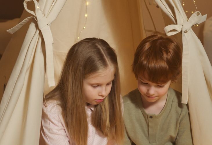 Dziecko czytające kolorową książkę edukacyjną siedzi na podłodze.