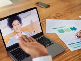 Kobieta pracuje na laptopie z wykresami wynagrodzeń na ekranie.